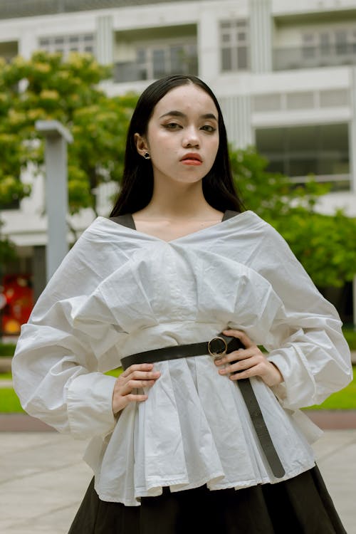 A Woman in White Blouse and Black Skirt Posing at the Camera