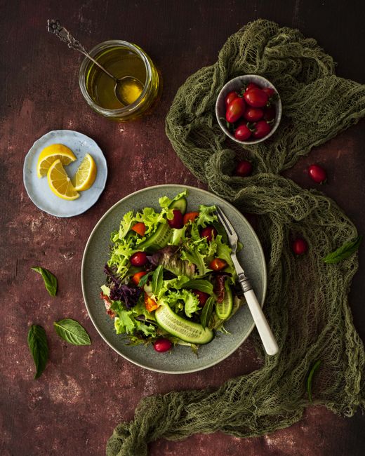 A colorful mixed salad with fresh greens, cucumbers, and tomatoes, elegantly styled on a rustic table.