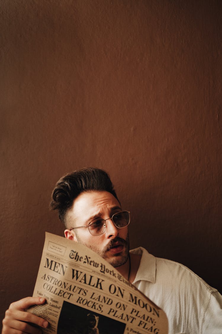 Young Man In Glasses Reading Newspaper