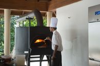 A chef prepares food using a traditional pizza oven indoors, showcasing culinary expertise.
