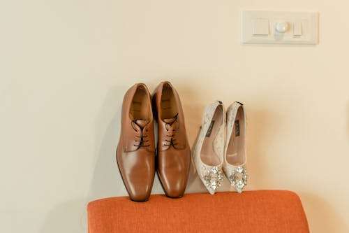 Brown Leather Shoes and Silver High Heels on a Couch 