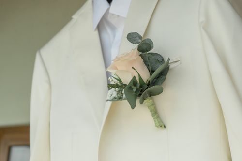 Free Close-up of a delicate rose boutonniere on a white suit jacket for a groom. Stock Photo