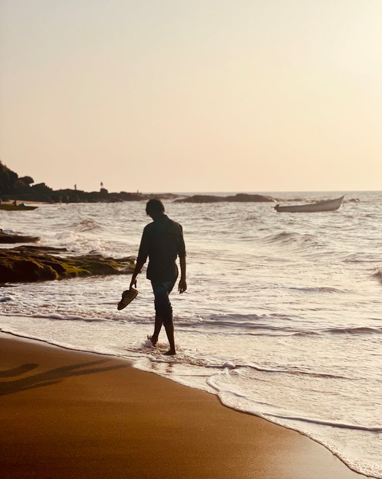 Man Carrying His Shoes Walking In The Beach