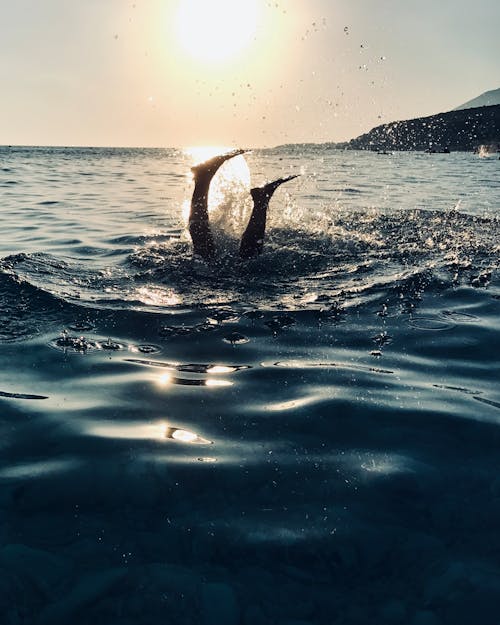 Person Swimming in the Ocean During Sunset 