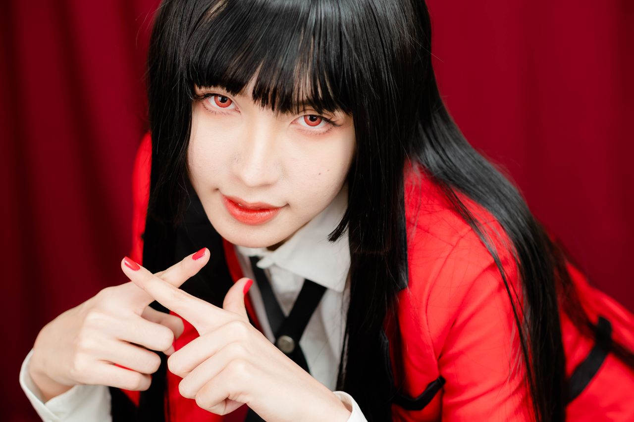 close up of a woman with long hair posing in a red blazer emphasizing