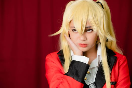 Portrait of a woman with blonde hair posing with a thoughtful expression, dressed in a red blazer indoors.