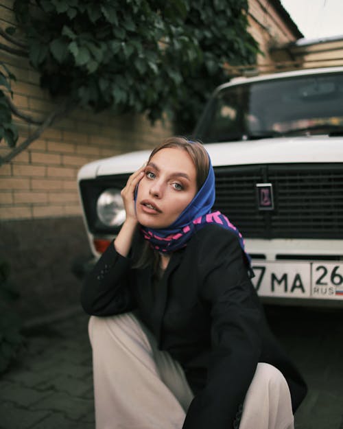 Woman in Blue Hijab and Black Long Sleeves Sitting on the Floor Near White Car 