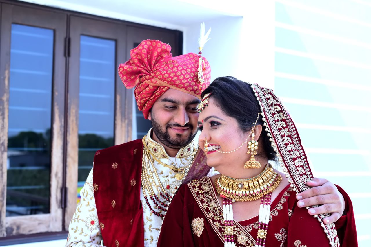 south asian couple in traditional wedding attire sharing a joyful mome