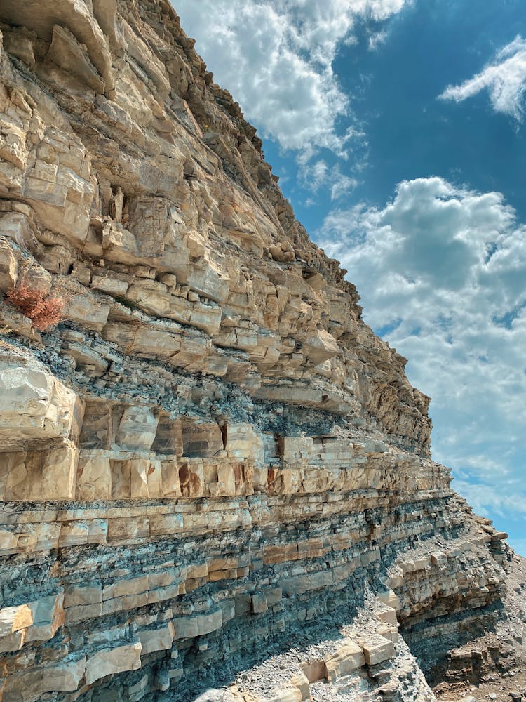 Compressed Rock Layers Formation Under Blue Sky And White Clouds