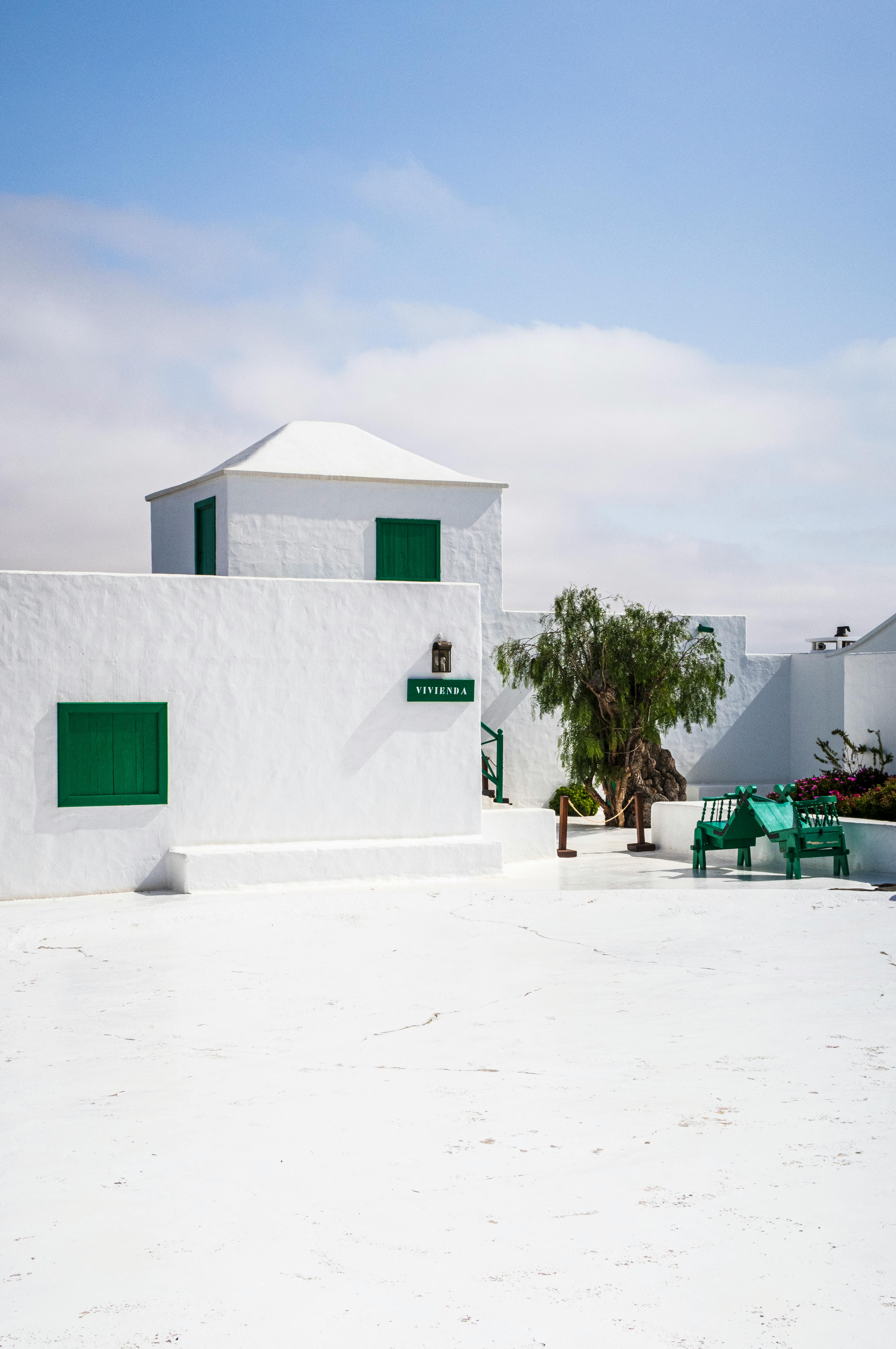 Bright whitewashed building with green accents under a blue sky in Lanzarote, Spain.