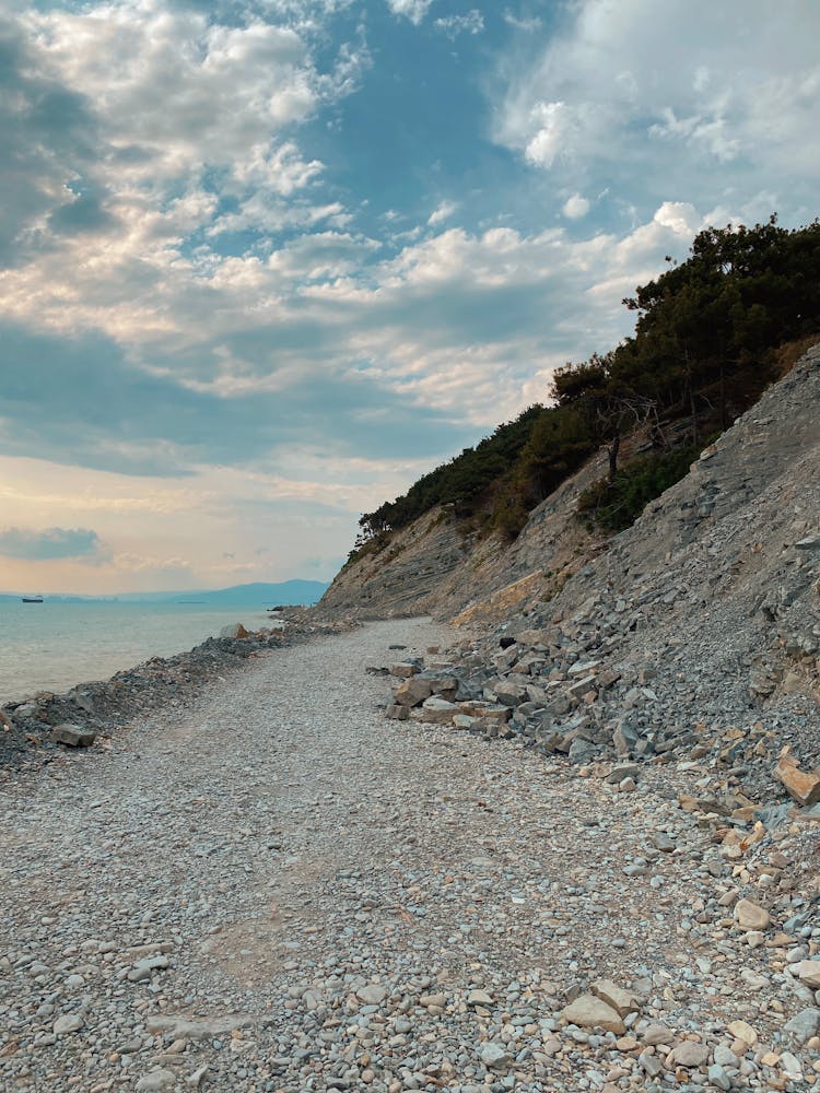 Mountain With Rocky Coastline Under Cloudy Sky