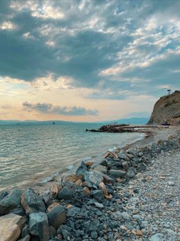 A serene coastal scene with rocky shore and tranquil sea under a cloudy sky.