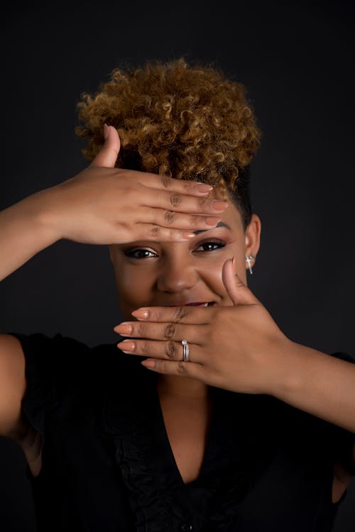 A Woman Covering Her Face while Looking at the Camera