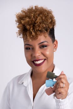 Portrait of a smiling woman holding colorful nail polish bottles against a white background.
