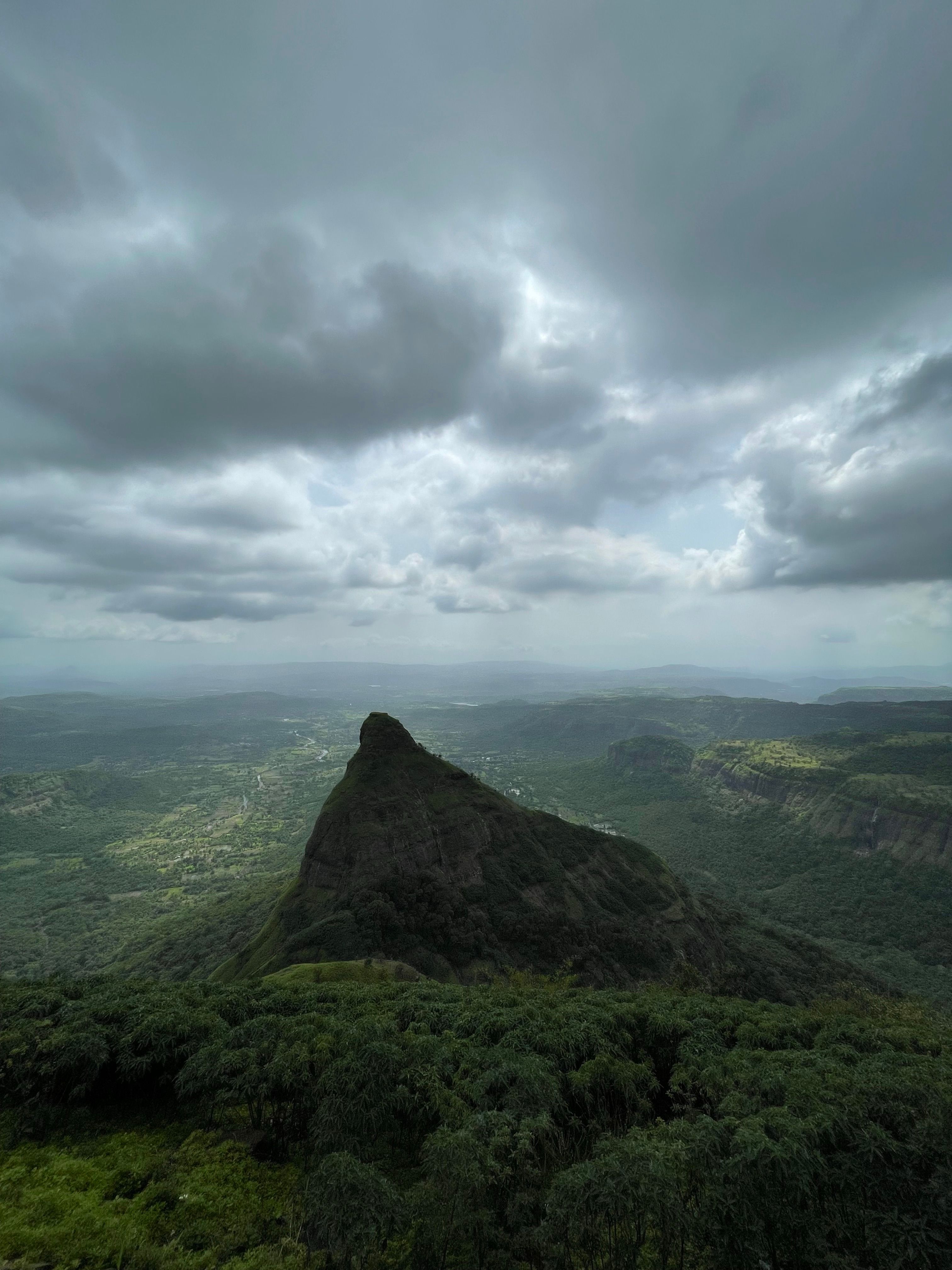 Stunning view of a lush mountain peak surrounded by a dramatic cloudy sky, highlighting the beauty of nature.