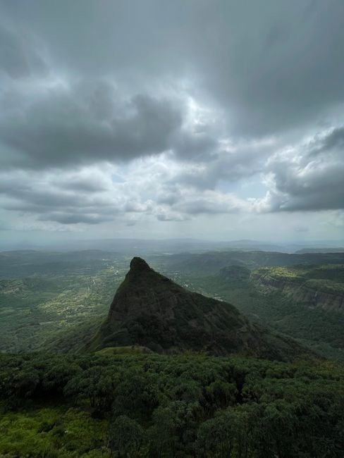 Stunning view of a lush mountain peak surrounded by a dramatic cloudy sky, highlighting the beauty of nature.
