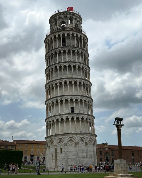Free Iconic Leaning Tower of Pisa with tourists and cloudy skies. Stock Photo