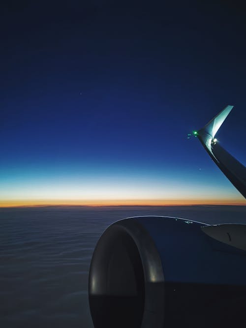 View of an Airplane Wing and Cloudscape at Sunset during a Flight 