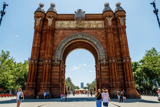 Explore the historic Arc de Triomf in Barcelona on a bright sunny day, showcasing its intricate architecture and vibrant atmosphere.