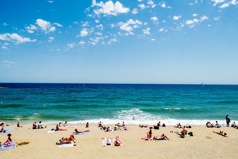 Fotomural Escena de playa concurrida con bañistas disfrutando de un día soleado junto al océano.