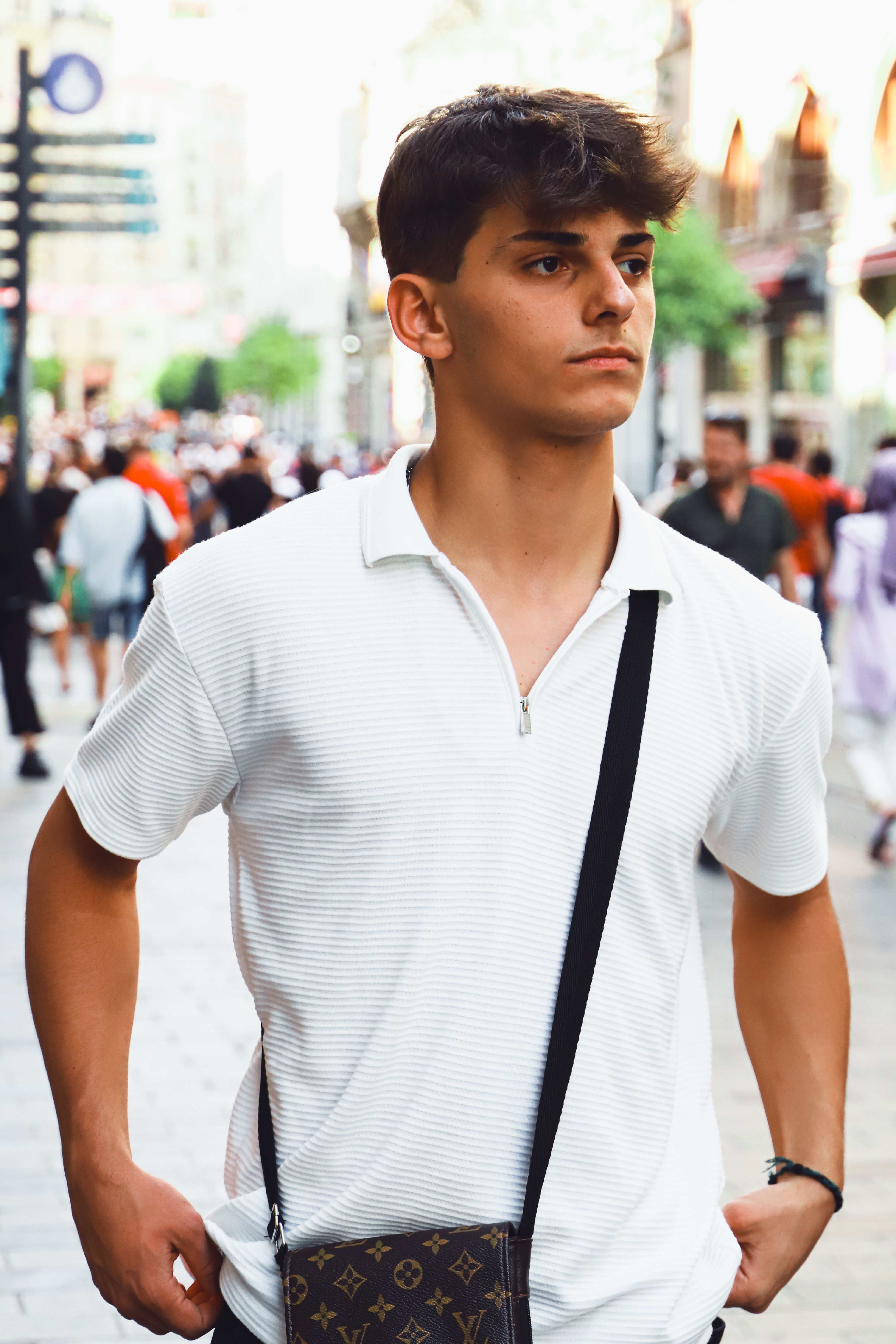 Casual portrait of a young man in a white shirt walking on a lively street in Istanbul.