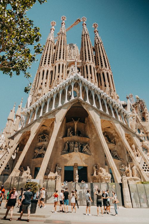A Low Angle Shot Of People Walking In Front Of La Sagrada Familia a-low-angle-shot-of-people-walking-in-front-of-la-sagrada-familia