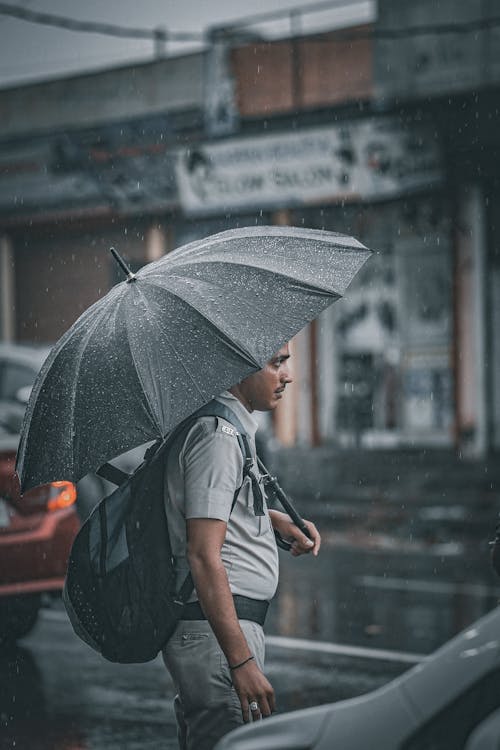 A Man in a Uniform Using an Umbrella while Raining