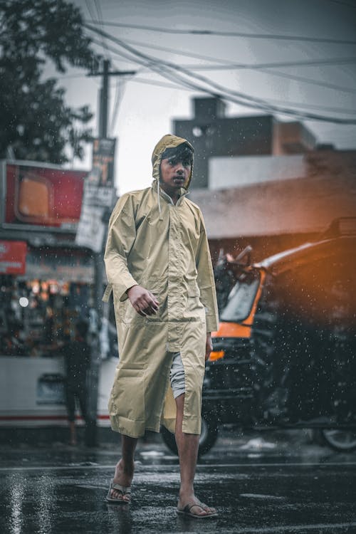 A Man in a Raincoat Crossing the Road while Raining