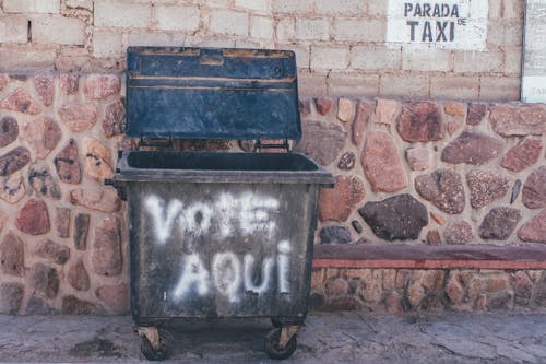 Trash Bin Beside a Stone Wall