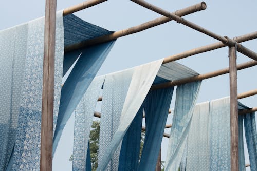 Синий и белый текстиль на деревянной стойке