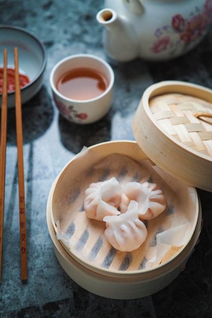 An elegant setup featuring steamed dumplings and tea on a marble table, perfect for a traditional meal.