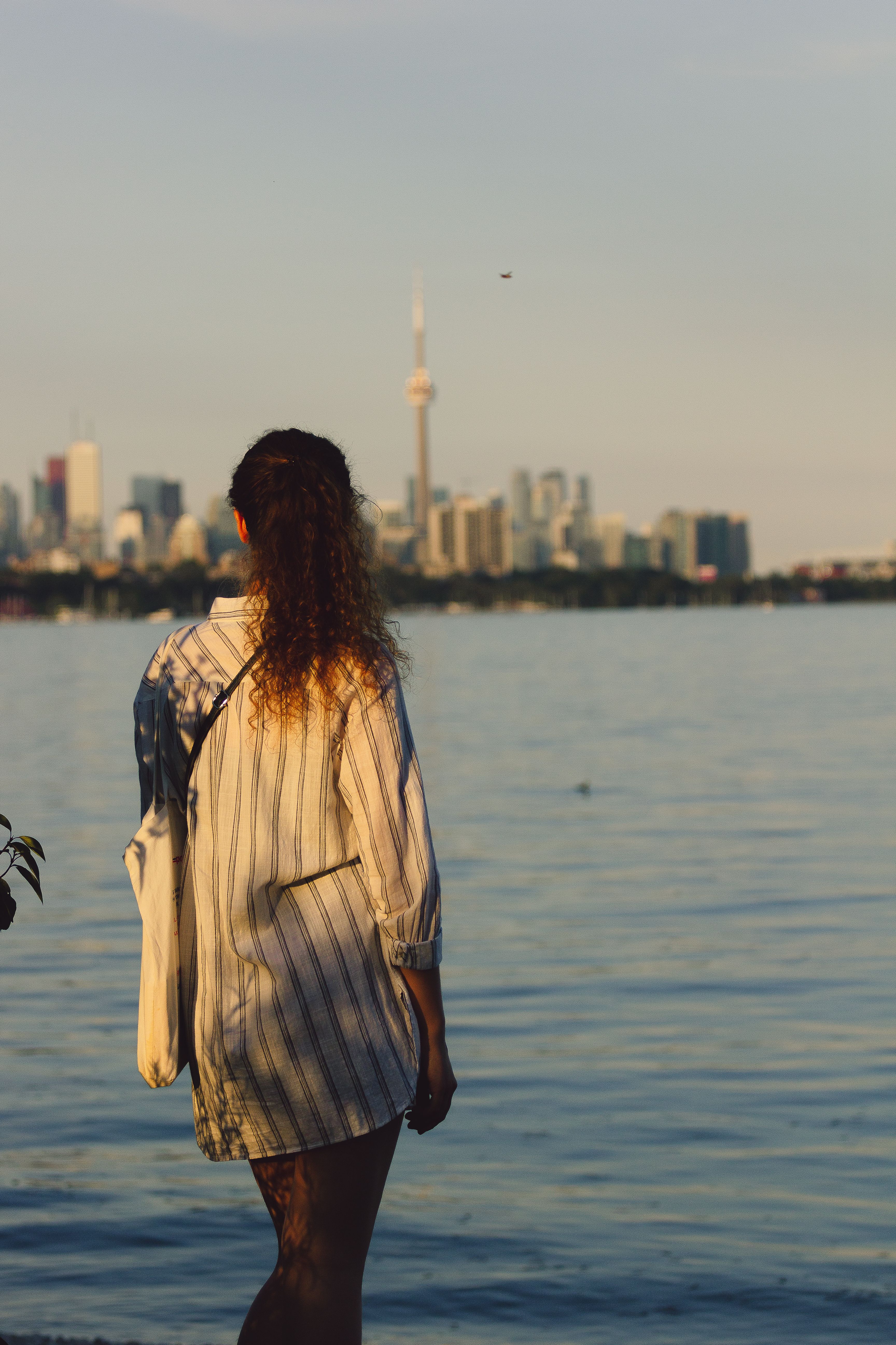 A Woman in Striped Dress Standing Near the Body of Water · Free Stock Photo