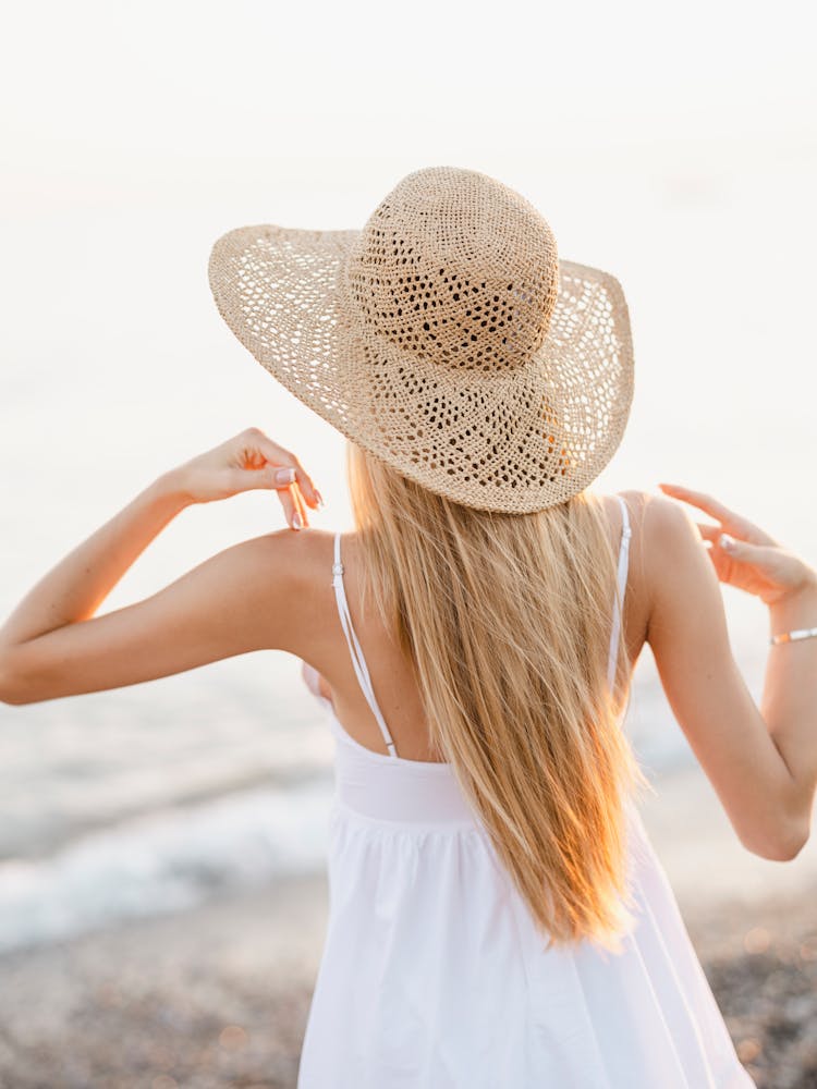 A Woman With A Straw Hat On The Beach