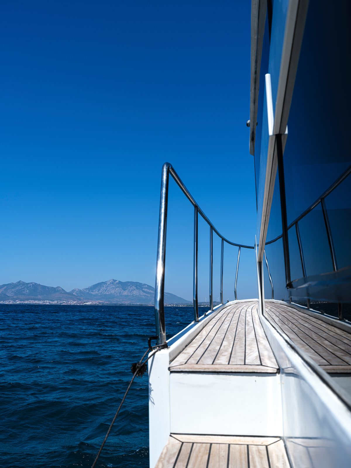 Looking forward along a yacht's deck toward distant mountains