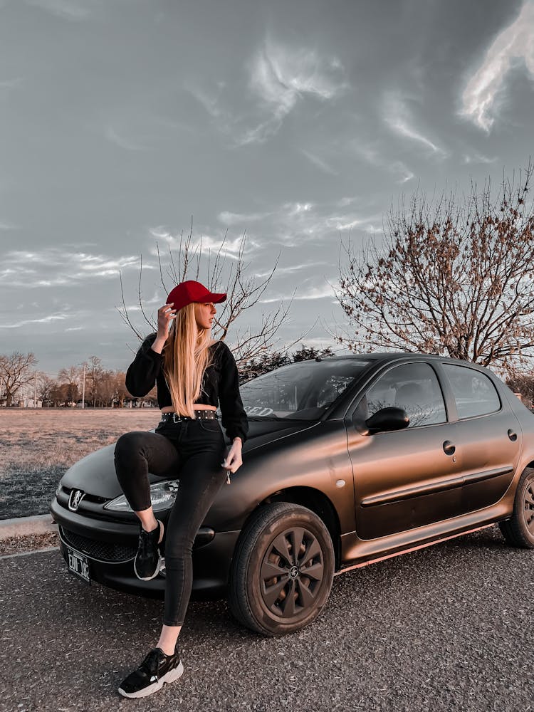 Woman In Red Cap Posing On Black Car