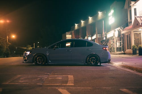 A Car Parked on the Street Near the Buildings at Night