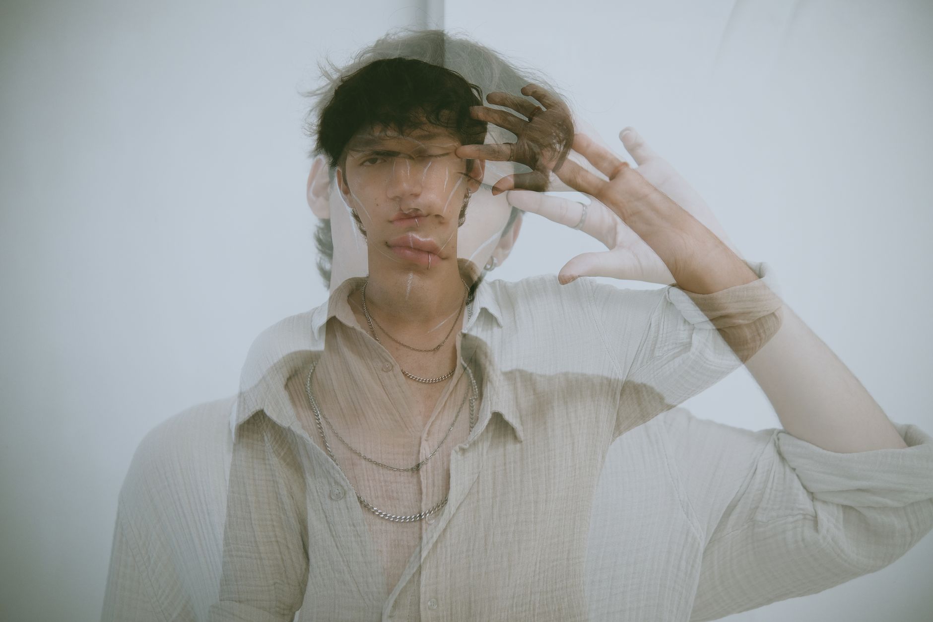 Creative double exposure portrait of a man posing against a white background.