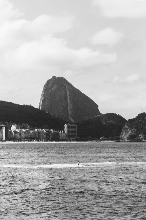 Free Scenic black and white photo of Sugarloaf Mountain and paddleboarder on Rio's coast. Stock Photo