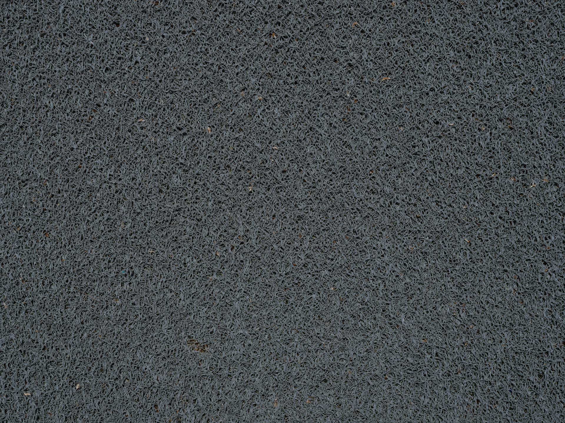 Detailed view of a gray synthetic doormat showcasing its fiber texture.