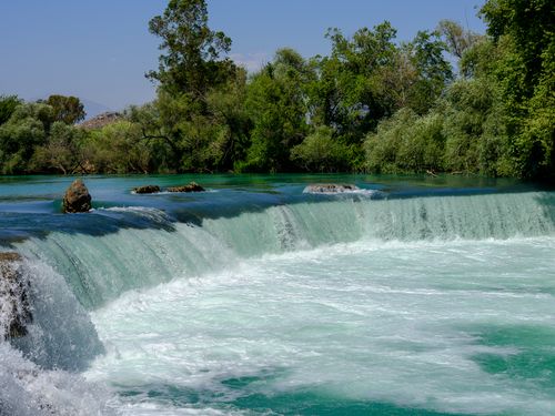 Free Captivating waterfall cascading through lush green forest on a sunny day, perfect for nature enthusiasts. Stock Photo