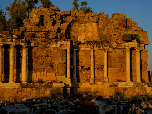 Free A stunning view of ancient Roman ruins bathed in warm evening sunlight. Stock Photo