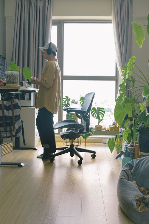 A Side View of a Man Wearing Headphones while Standing Near the Chair