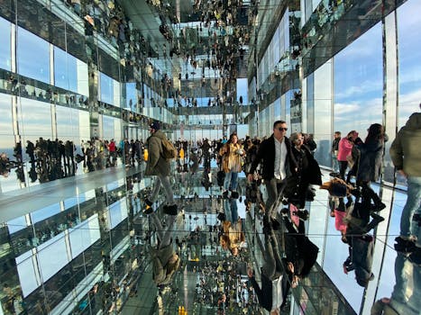 Crowded glass corridor with stunning reflections creating a mesmerizing illusion.