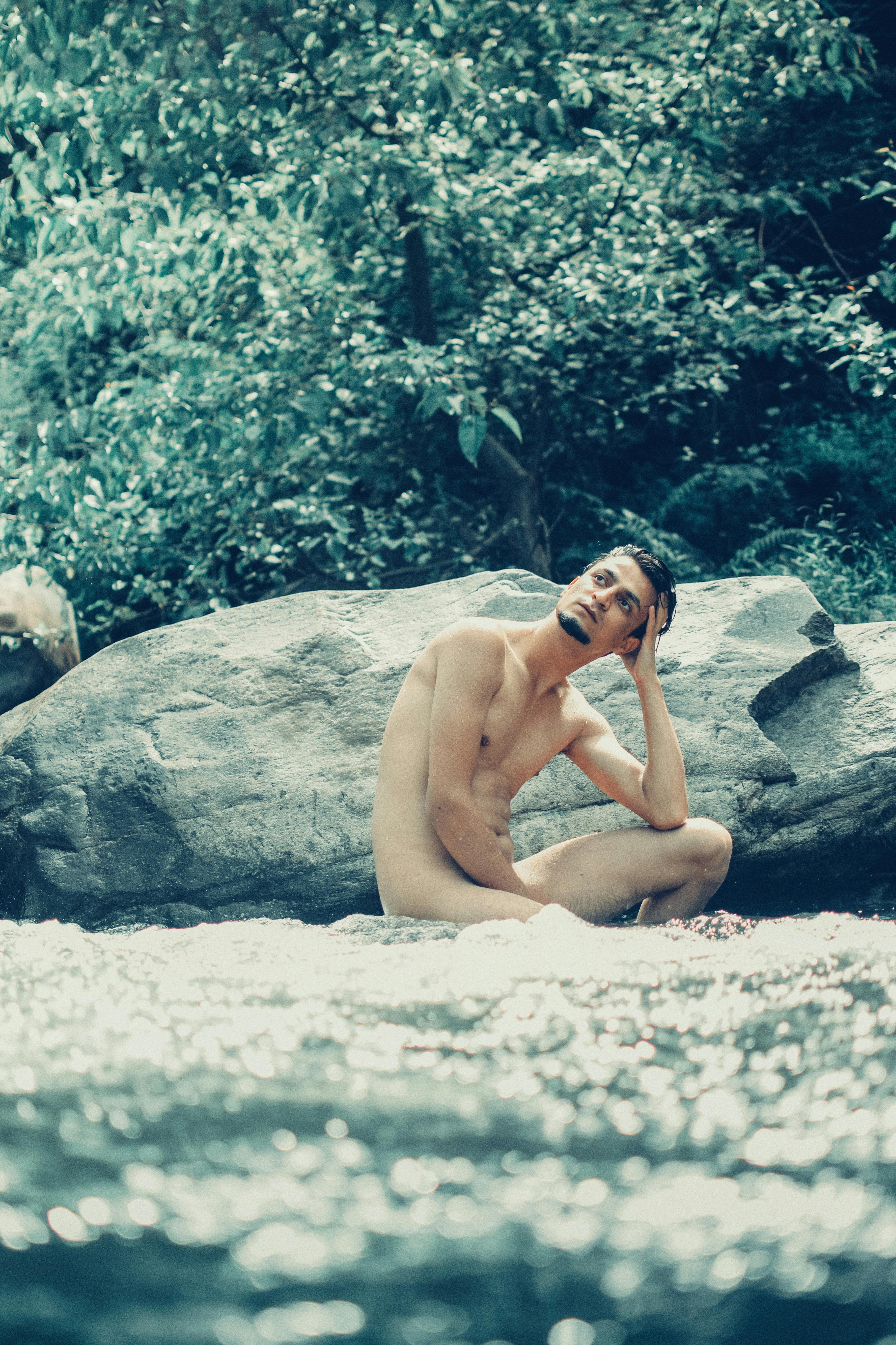 A Naked Man Sitting Near the Rock · Free Stock Photo