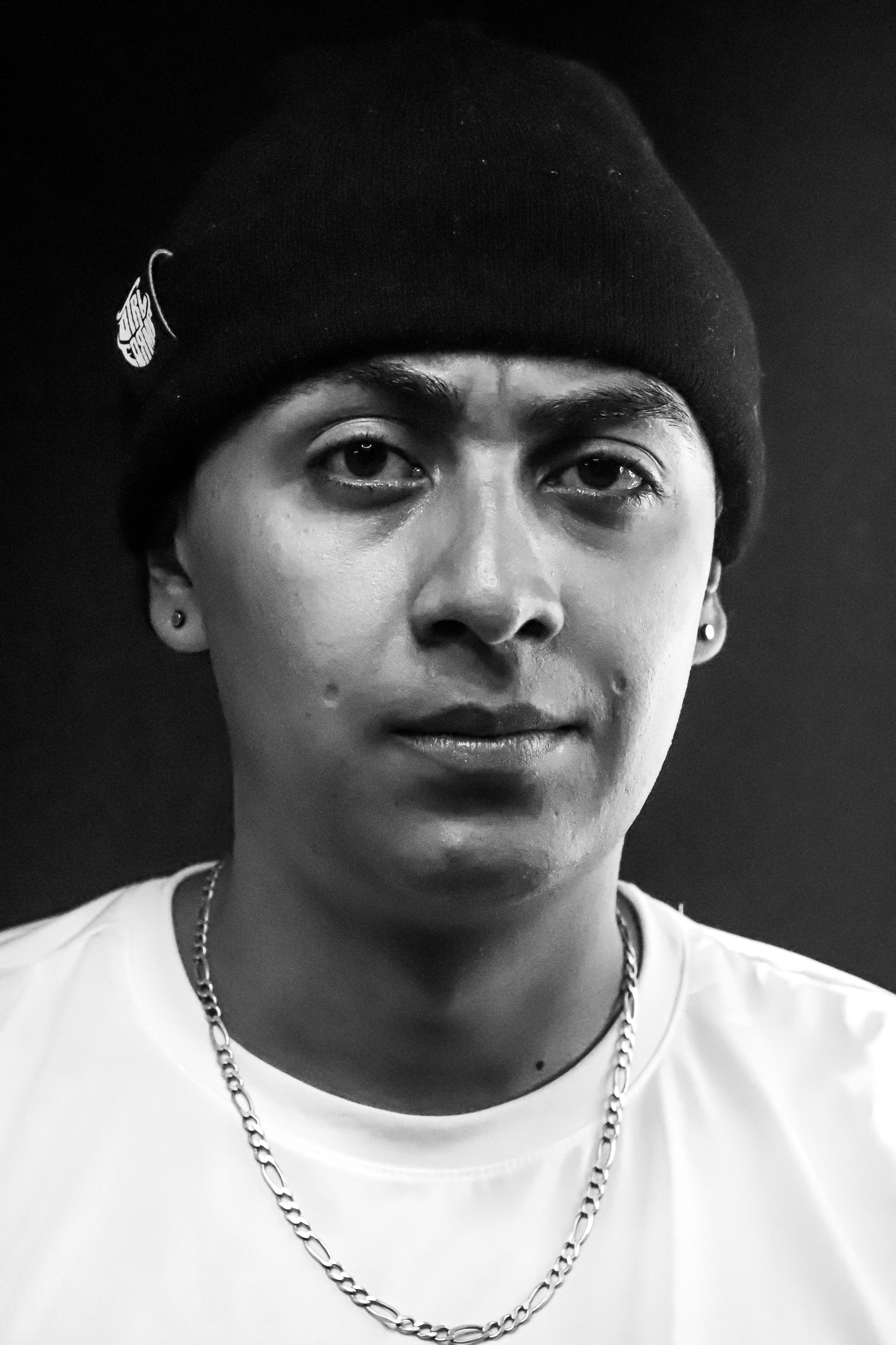 Black and white portrait of a man in a beanie with a chain necklace, taken in Bogotá, Colombia.