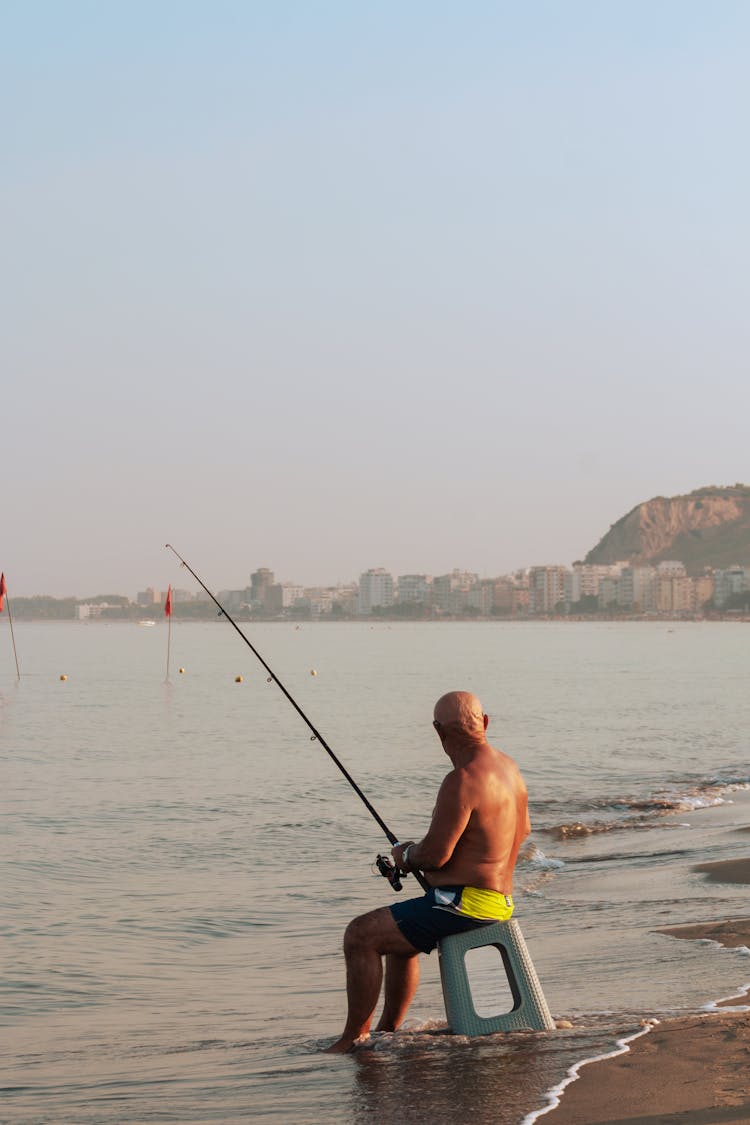 Shirtless Elderly Man Fishing On Sea