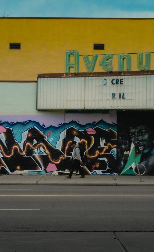 Free Vibrant graffiti wall on an urban street with a pedestrian walking by in Edmonton, Canada. Stock Photo
