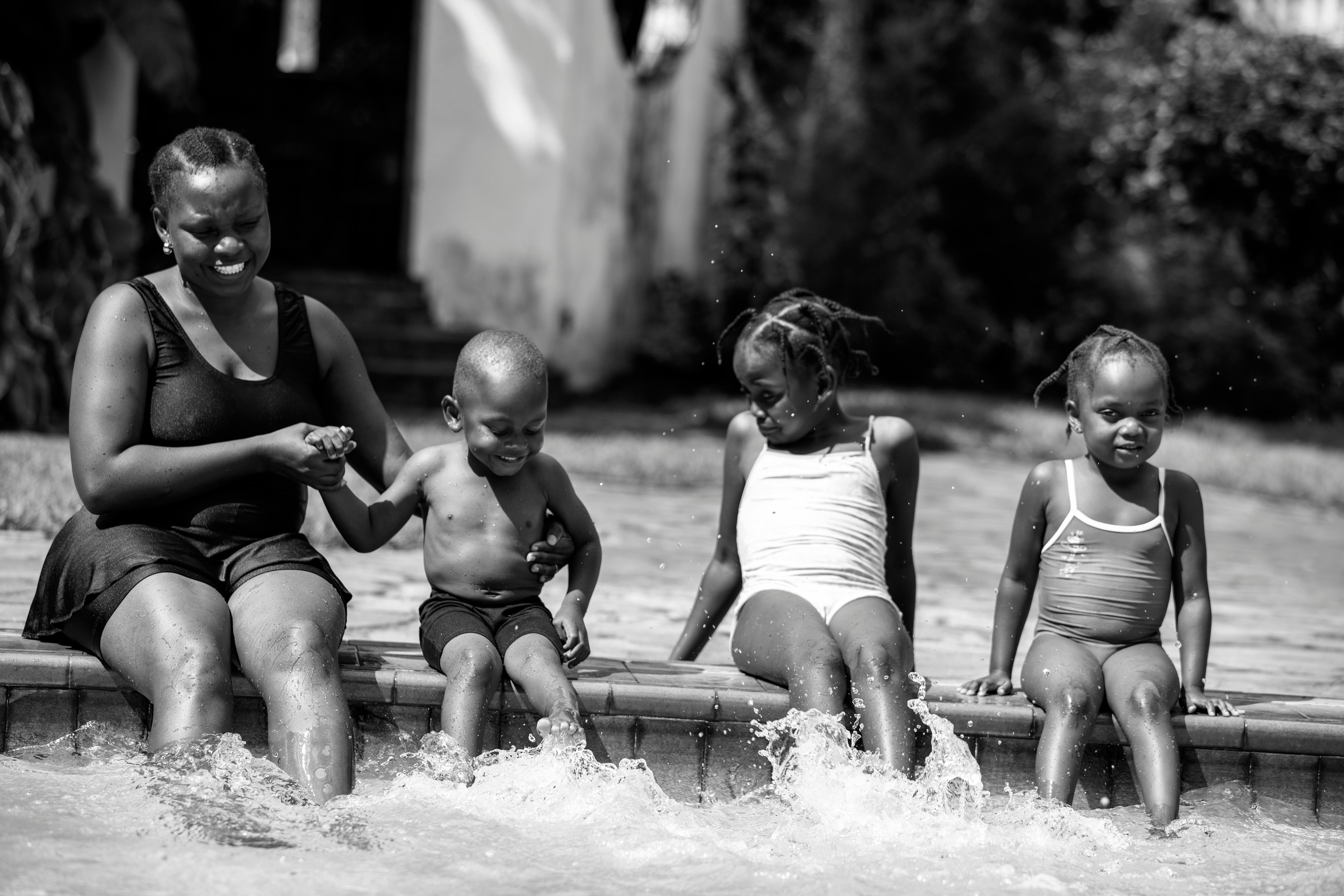A heartwarming scene of a woman with three children enjoying a sunny pool day in grayscale. - Photo by Josiah Matthew on Pexels