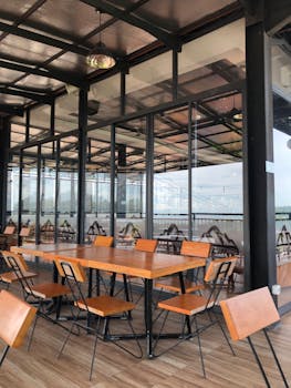 Stylish dining area with wooden furniture and glass walls in contemporary design.