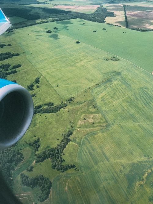 Free Captivating aerial shot showcasing lush green fields and airplane engine view. Stock Photo